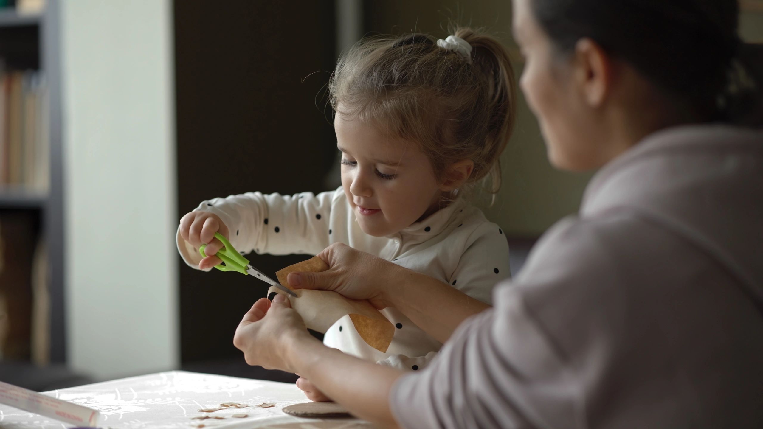 Child and adult doing a hands-on fine motor craft activity at a table